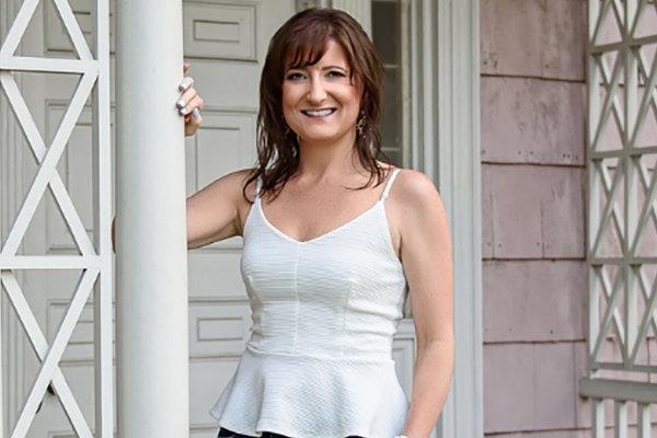 Nationally-recognized speaker, author, and entrepreneur, Jaime Spencer, stands on front porch and smiles.