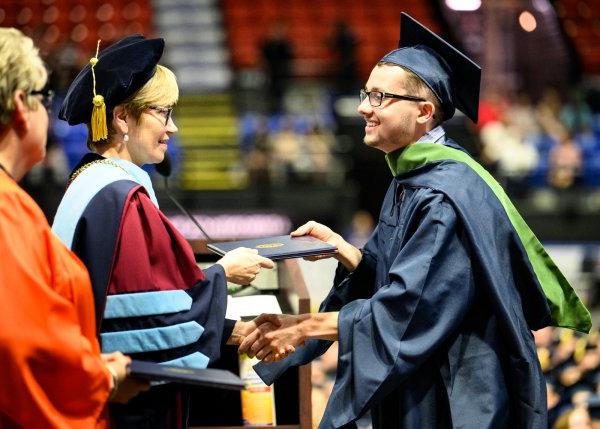 A gradute receives their diploma from President Laura Casamento during the 2022 Commencement ceremony.